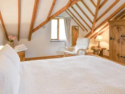 a bedroom with a white bed and a chair at Hafan Prysor in Trawsfynydd