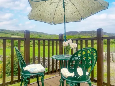 a table and two chairs with an umbrella on a deck at Hafan Prysor in Trawsfynydd