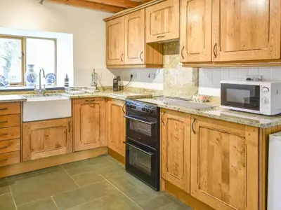 a kitchen with wooden cabinets and a microwave oven at Hafan Prysor in Trawsfynydd