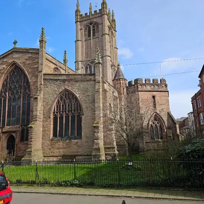 an old stone church with a tower on a street at Ground floor well appointed cosy flat in Ludlow in Ludlow
