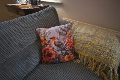 a blue couch with a pillow and a bird on it at Ground floor well appointed cosy flat in Ludlow in Ludlow