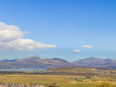 a view of a field with mountains and a body of water at Bramble Bank in Harlech