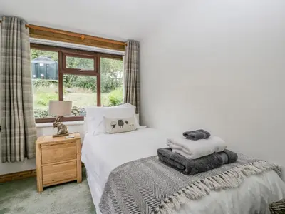a bedroom with a bed with white sheets and a window at Fieldfare in Leominster
