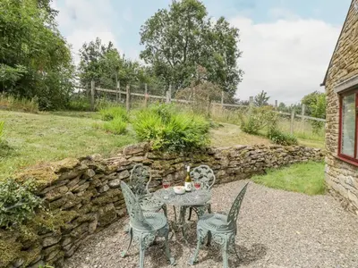 a patio with a table and chairs and a stone wall at Fieldfare in Leominster