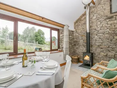 a dining room with a table and a fireplace at Fieldfare in Leominster