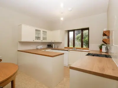 a kitchen with white cabinets and a wooden counter top at Bullfinch Cottage in Leominster