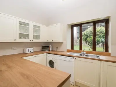 a kitchen with white cabinets and a sink at Bullfinch Cottage in Leominster