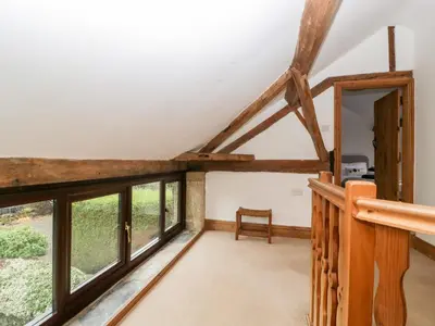 an attic room with large windows and a staircase at Bullfinch Cottage in Leominster