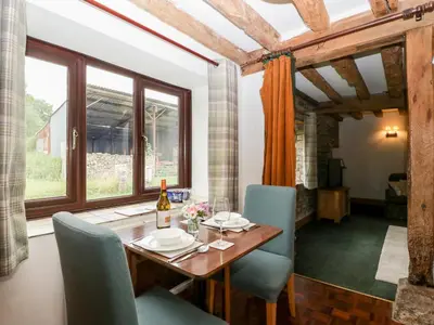 a dining room with a wooden table and blue chairs at Redstart Cottage in Leominster