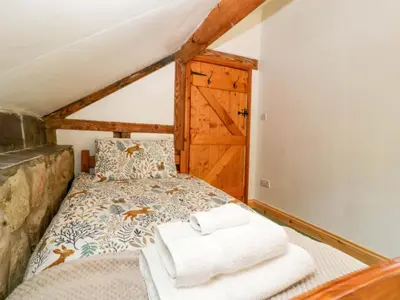a bedroom with a bed with towels on it at Redstart Cottage in Leominster
