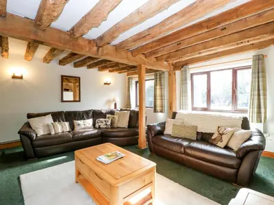 a living room with leather couches and a table at Redstart Cottage in Leominster