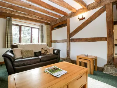 a living room with a leather couch and a coffee table at Redstart Cottage in Leominster