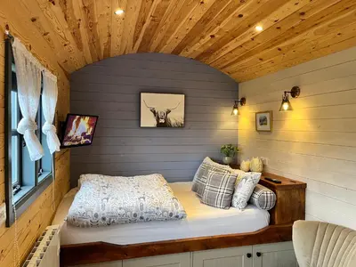 a bed in a small room with a wooden ceiling at Oakies Farm Stays in Llandovery