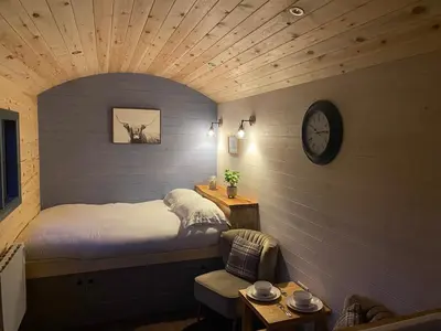 a bedroom with a bed and a clock on the wall at Oakies Farm Stays in Llandovery