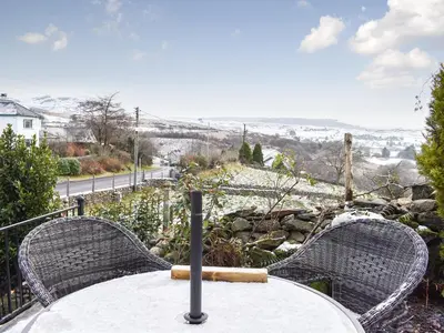 a table with two wicker chairs sitting on top of a table at Summerhill Tanyrhos in Blaenau-Ffestiniog