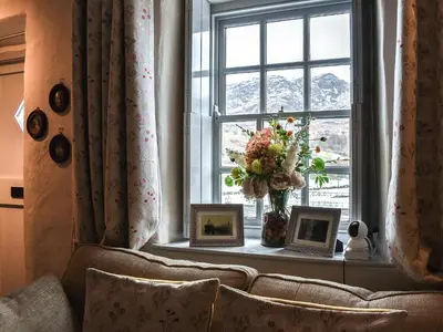 a living room with a window with a vase of flowers at Summerhill Tanyrhos in Blaenau-Ffestiniog