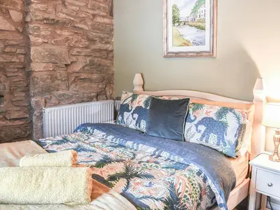 a bedroom with a bed and a stone wall at Summerhill Tanyrhos in Blaenau-Ffestiniog