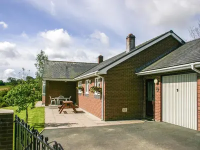 a brick house with a patio in front of it at Gwynfan Bungalow in Llandrindod Wells
