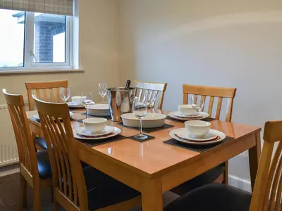 a dining room table with chairs and a wooden table with wine glasses at Gwynfan Bungalow in Llandrindod Wells