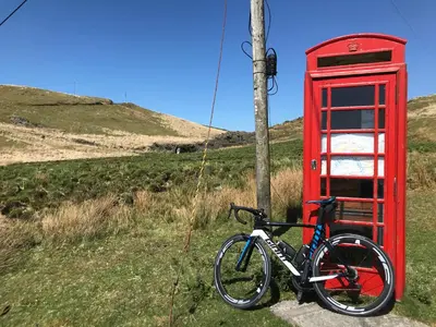 a bike is parked next to a red phone booth at The Stables in Tregaron