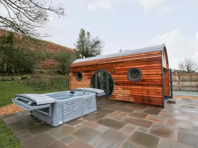 a small wooden shed with a hot tub on a patio at Callow Pod in Shrewsbury