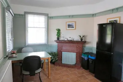 a kitchen with a fireplace and a table and a refrigerator at Country Mansion - Private Annexe in Llanwrda