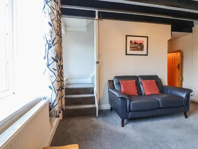 a living room with a leather couch and stairs at Ynys in Dyffryn