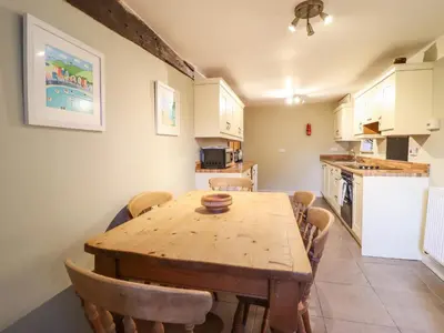 a kitchen with a wooden table and some chairs at Ynys in Dyffryn