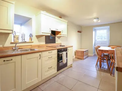 a kitchen with white cabinets and a sink and a table at Ynys in Dyffryn