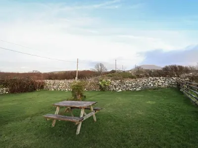 a picnic table in a field with a stone wall at Ynys in Dyffryn