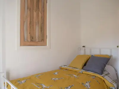 a bed with a yellow comforter in a room at Tan Y Llidiart in Llangedwyn