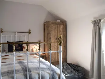 a bedroom with a bed and a wooden cabinet at Tan Y Llidiart in Llangedwyn
