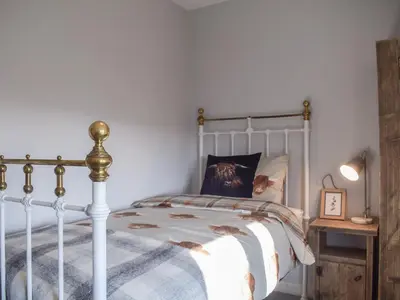 a bedroom with a white bed with a cat pillow at Tan Y Llidiart in Llangedwyn