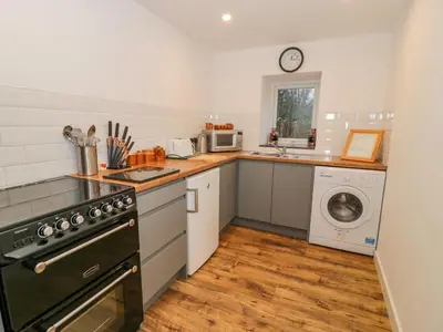 a kitchen with a stove and a sink and a dishwasher at Bronwen House in Llanbedr