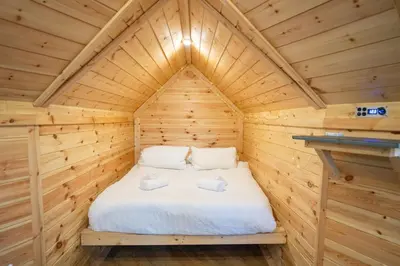 a bed in a wooden cabin with two towels at Chestnut Tree House with Hot tub & Sauna in Barmouth