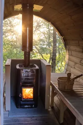 a wood stove in a cabin with a window at Chestnut Tree House with Hot tub & Sauna in Barmouth