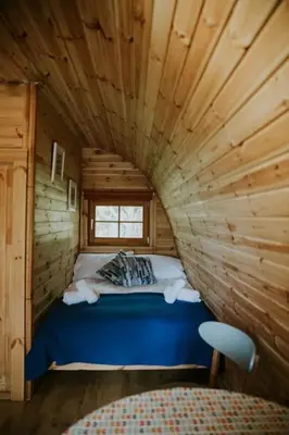a bed in a log cabin with a window at Snowdonia Mawddach Cabin and hot tub Glamping in Barmouth