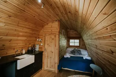 a bathroom with a bed in a wooden cabin at Snowdonia Mawddach Cabin and hot tub Glamping in Barmouth