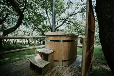 a wooden barrel with a bench on a wooden deck at Oak SPECIAL WINTER OFFERS - Hot tub in Barmouth