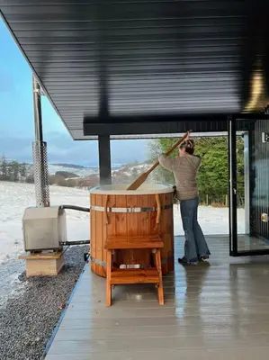 a person standing in a building with a broom at Quirky, Luxury Hideaway in Llanbrynmair