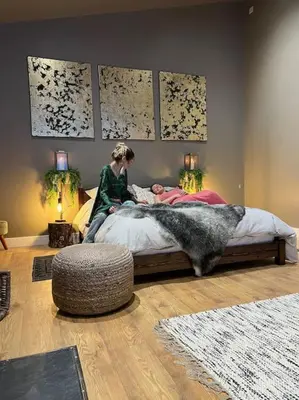 a woman sitting on a bed in a bedroom with a dog at Quirky, Luxury Hideaway in Llanbrynmair