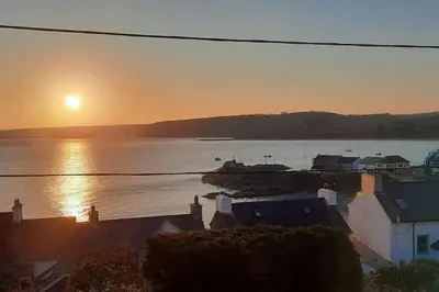 a sunset over a body of water with houses at Arvonia sleeps 7, sea views, dog friendly in New Quay
