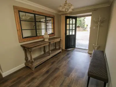 a hallway with a mirror and a table and a chair at The Marshes in Welshpool