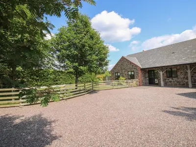 a barn with a fence next to a building at The Marshes in Welshpool