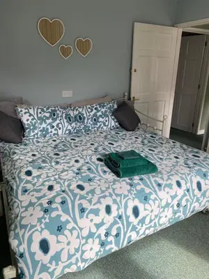 a bedroom with a bed with a blue and white comforter at The Coach House at Copper Hall in Leominster