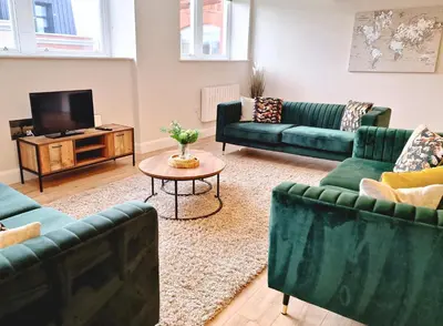 a living room with green couches and a tv at The Academy House by Bevolve in Shrewsbury