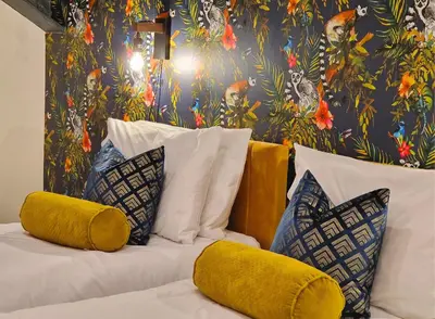 a bed with yellow pillows and a floral wallpaper at The Academy House by Bevolve in Shrewsbury