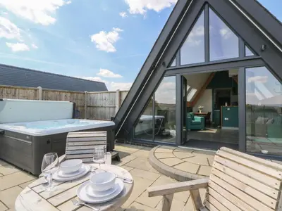 a patio with a hot tub and a table and chairs at Kerry Hill - The Sheepfold in Llandrindod Wells