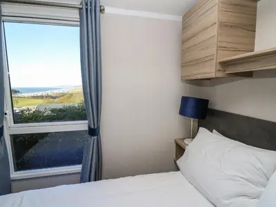 a bedroom with a bed and a large window at Gwent 74 in Borth