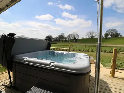 a hot tub on a deck with a view of a field at Otter in Nantmel
